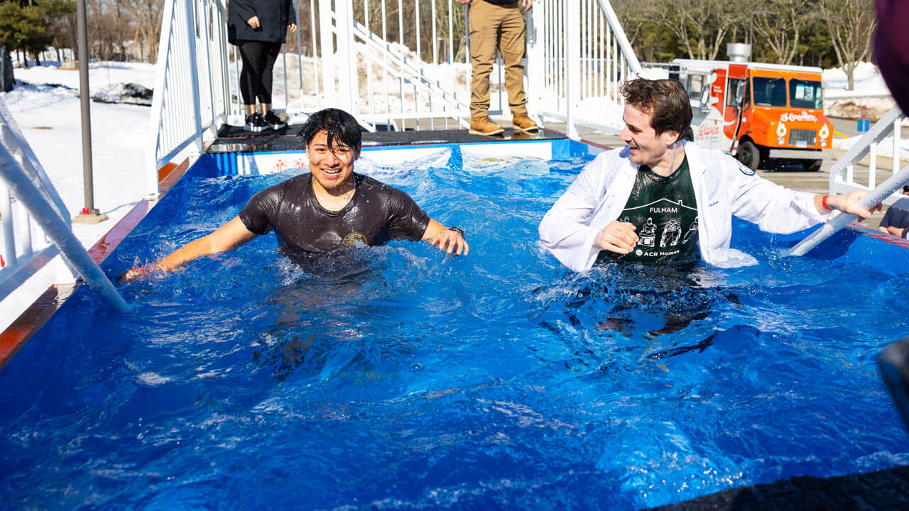 Students stand in polar plunge dunk tank in the freezing cold