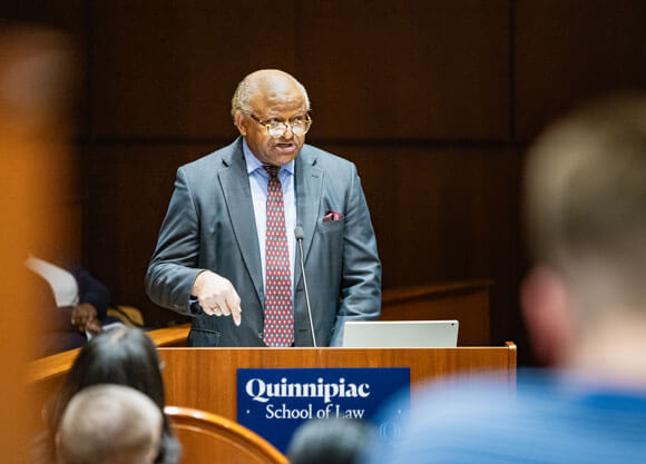 An individual speaks to a crowd while standing behind a podium.