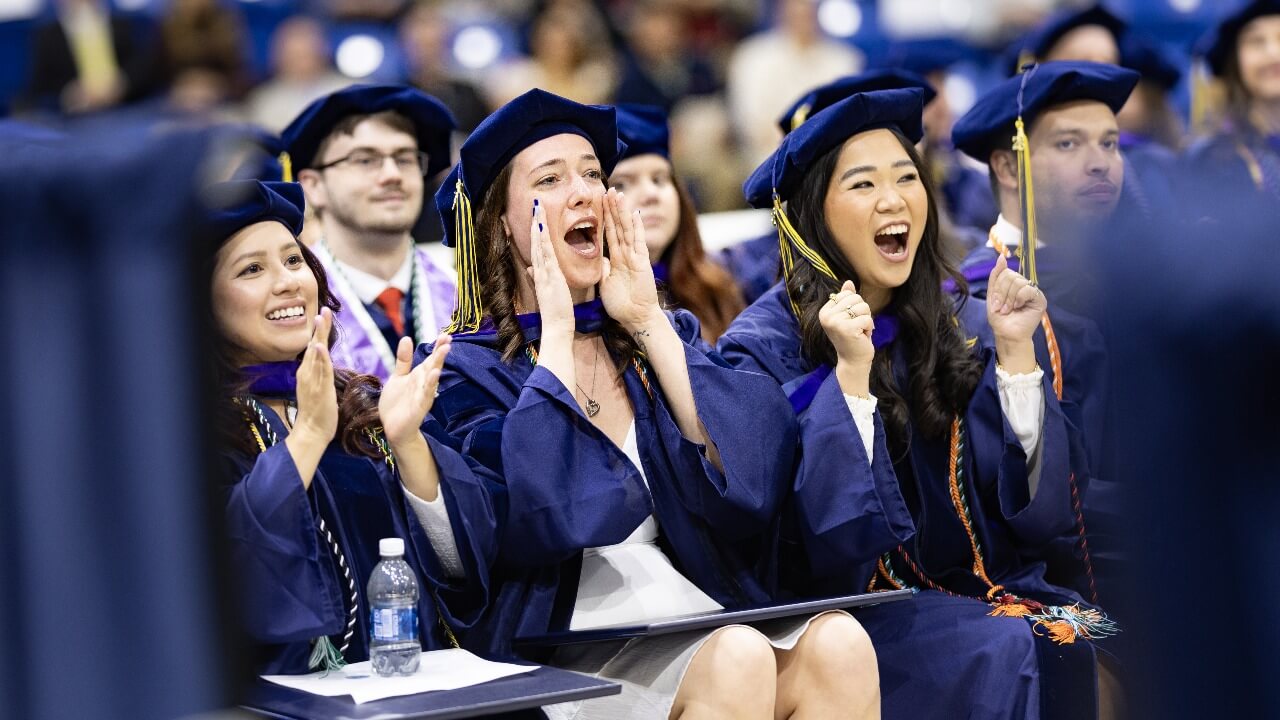 Graduates cheer and clap together during ceremony