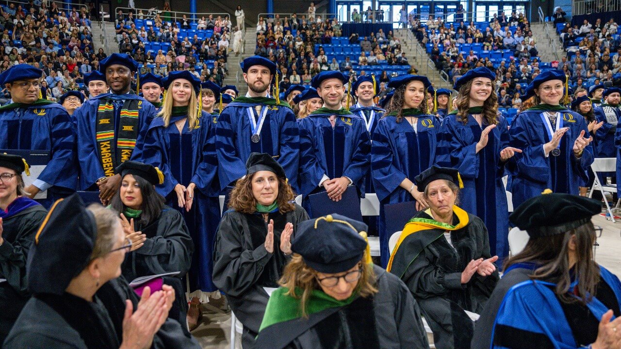 Crowd of graduates stand.