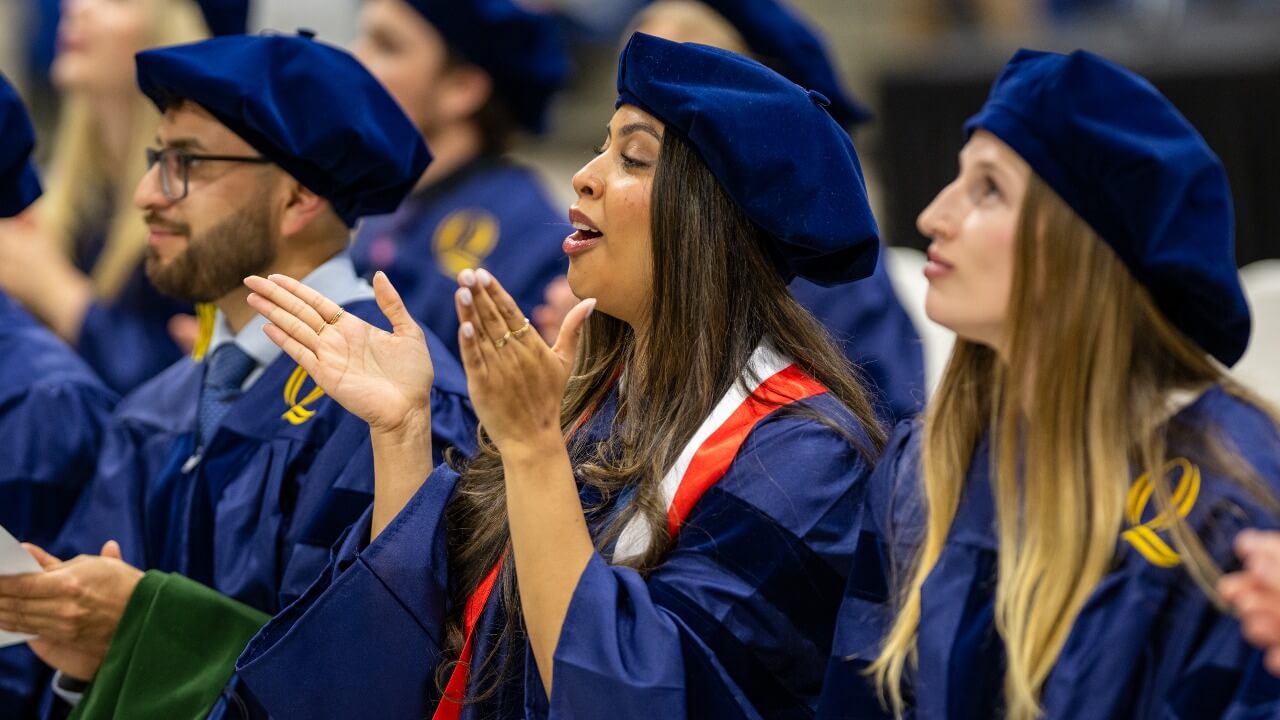 Graduates clap in their seats.