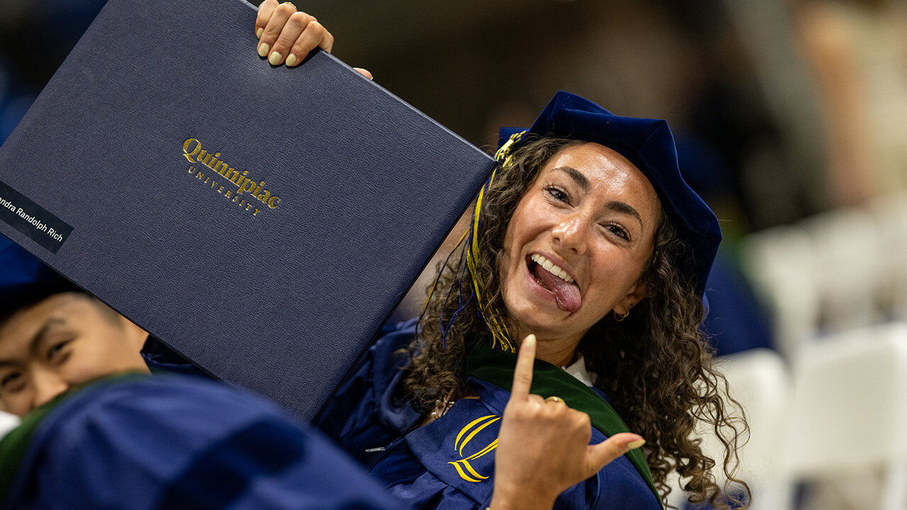 Graduate posing with their diploma