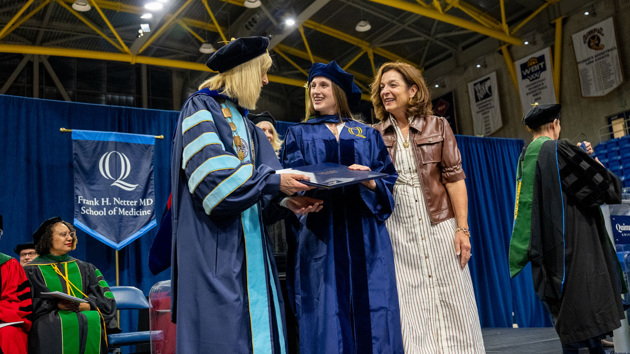 President Marie Hardin hands a 2026 School of Medicine graduate her diploma on stage