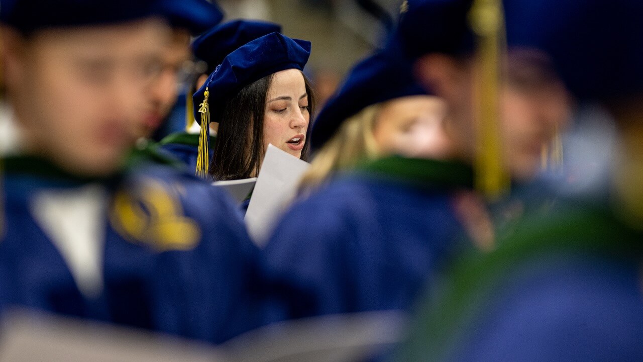 Graduate reads the 2026 Commencement booklet