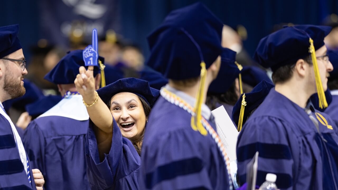 Graduate holds up a foam finger reading #1 with excitement