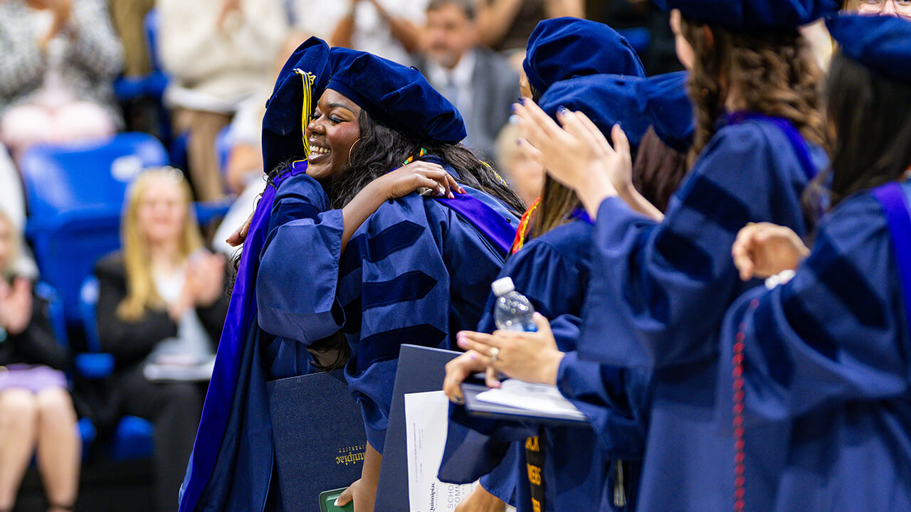 Graduates hug in celebration