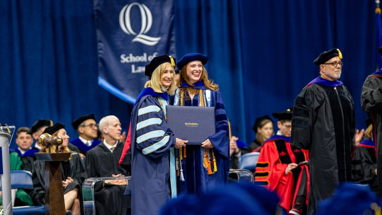 President Hardin stands with graduate and holds up diploma