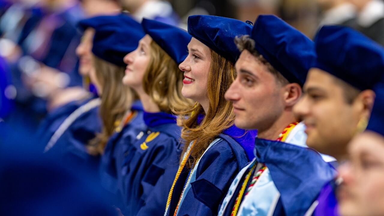 Graduate smiles as she sits with her classmates at Commencement