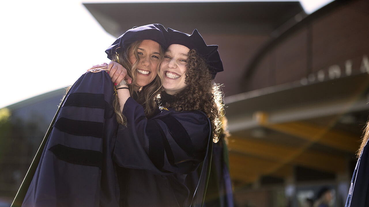 Graduating students hug in front of the M&T Bank Arena