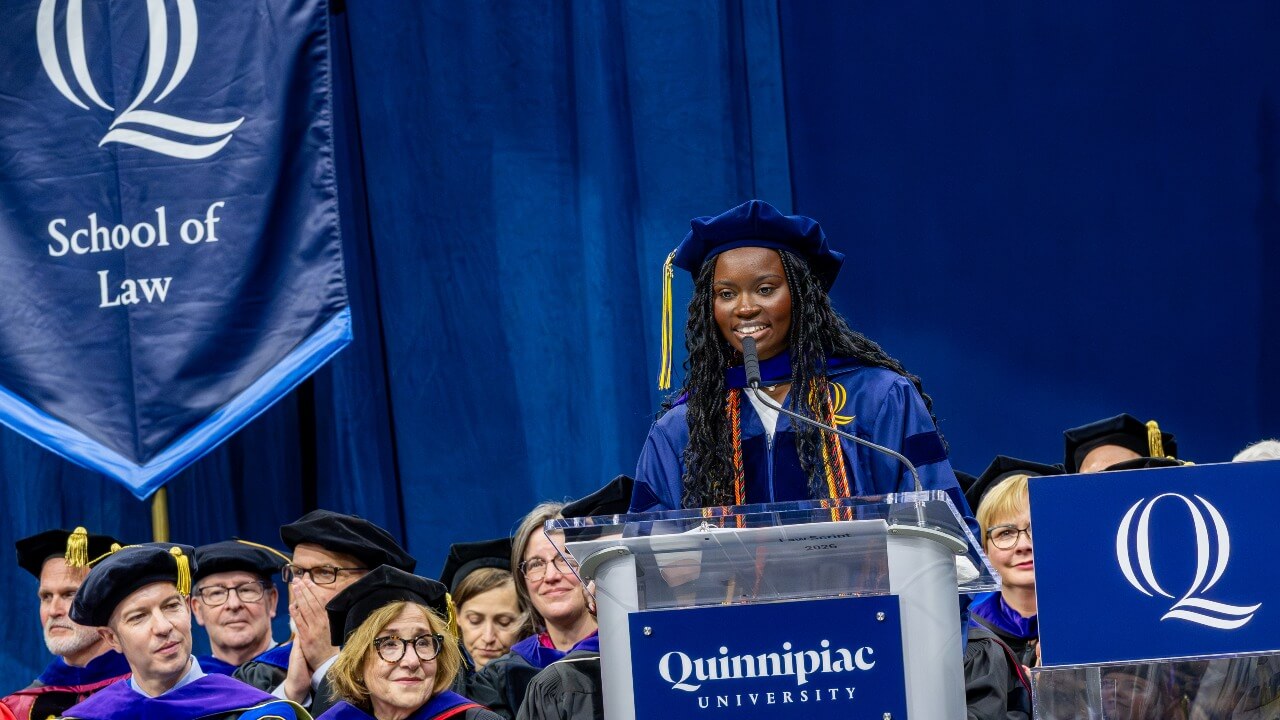 Student speaker standing at the podium and smiling at graduates
