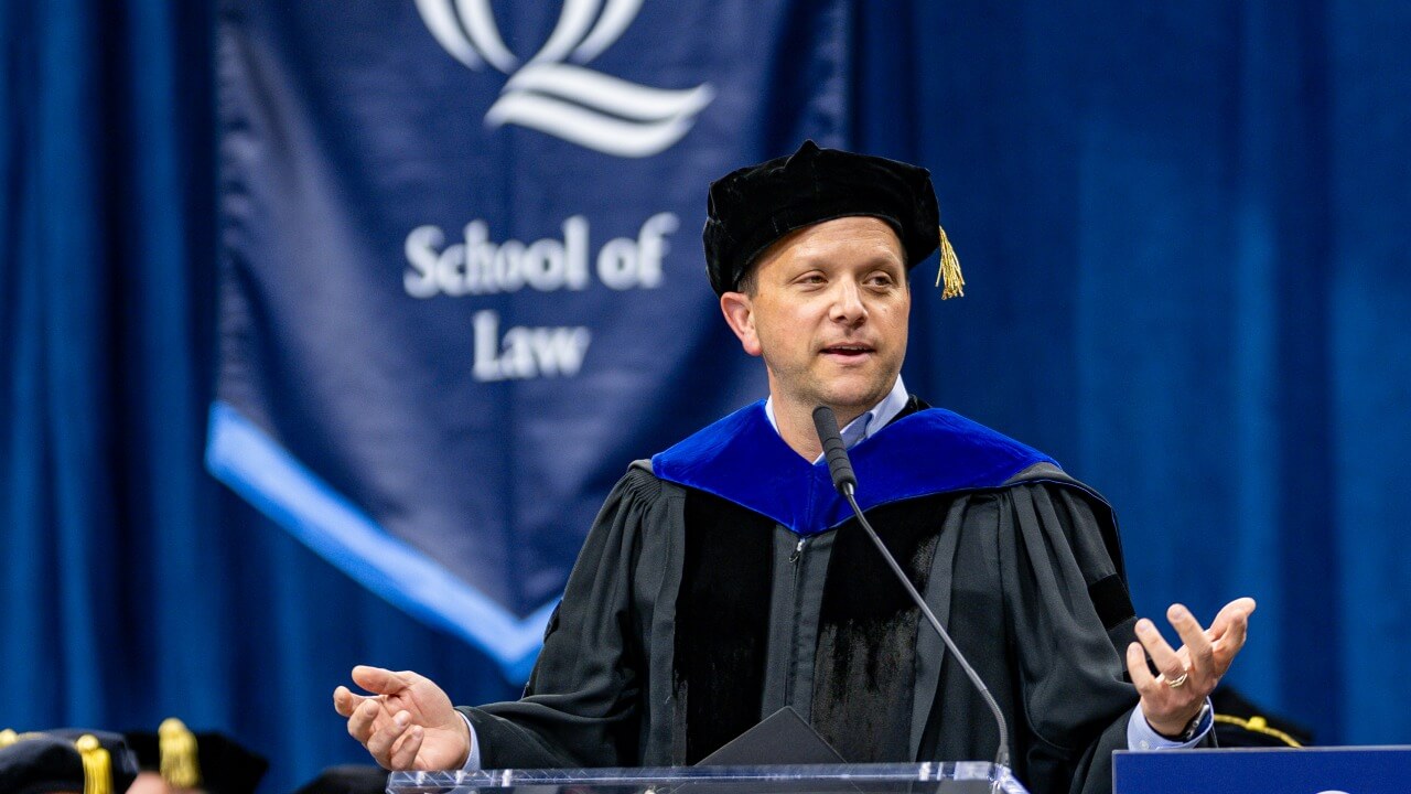 Alumni greeter standing at the podium and smiling