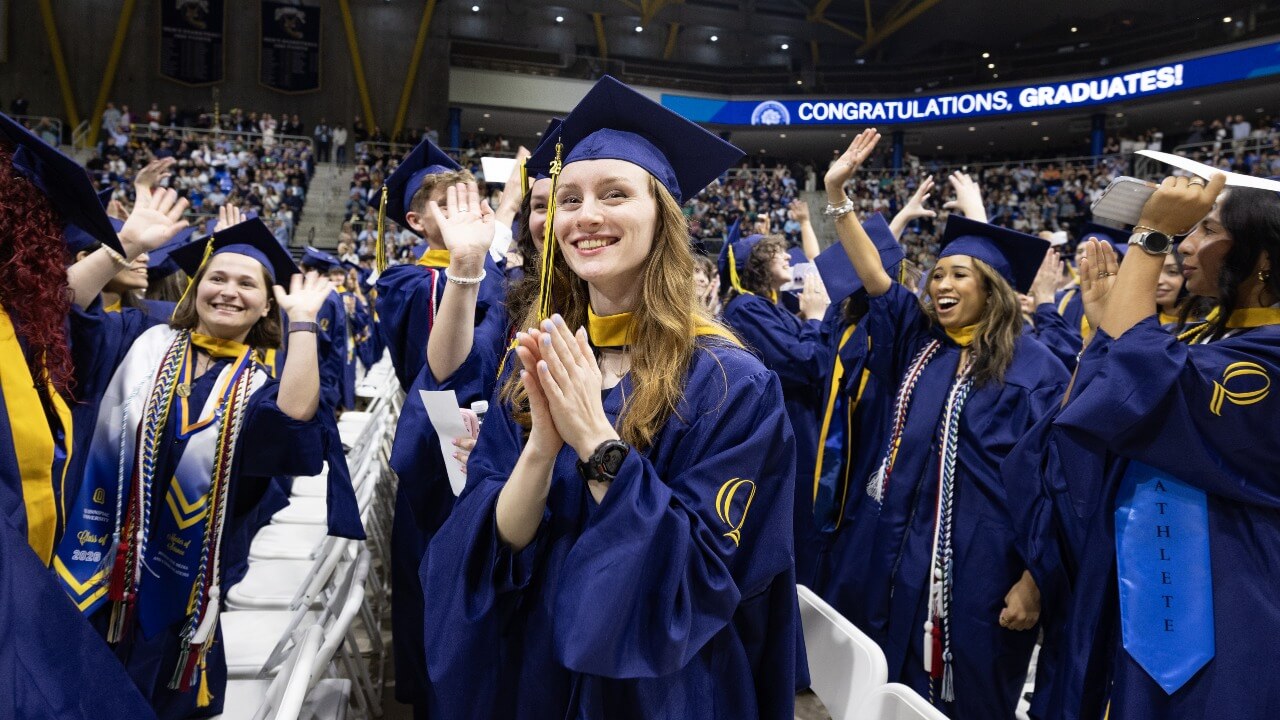 Graduates in caps and gowns clap.