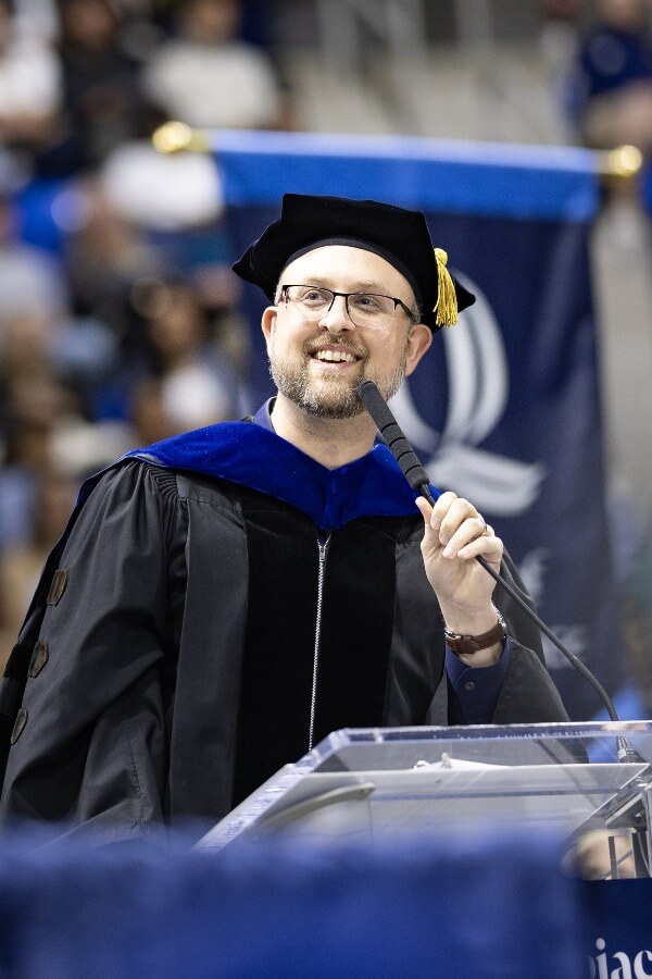 Keynote speaker stands at the podium and addresses the graduates