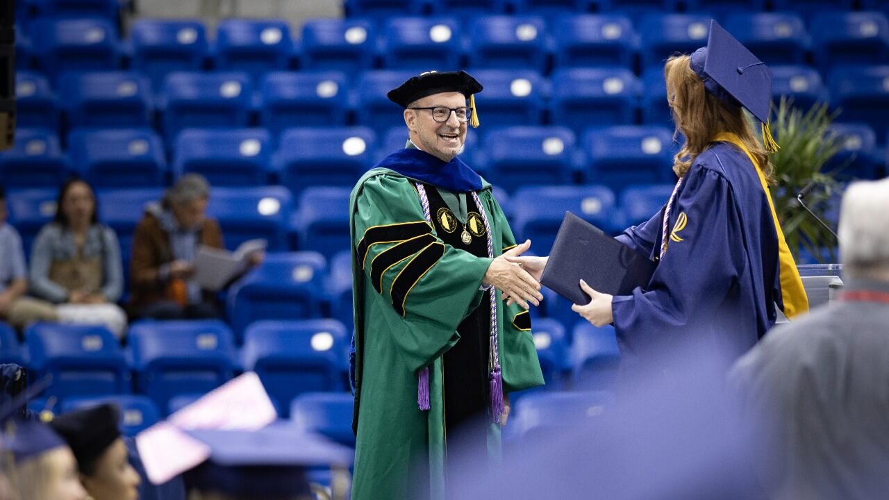 Graduate receives degree on stage.