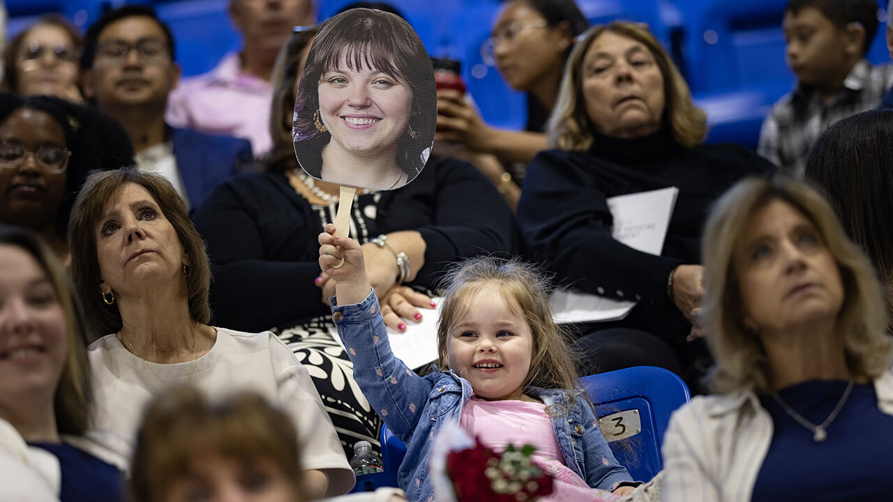 Families celebrate in crowd with custom sign