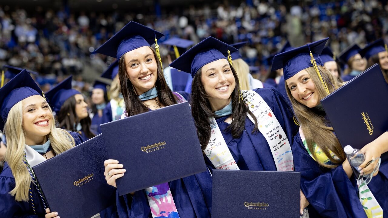 Four students stand together with their diplomas to pose for a picture