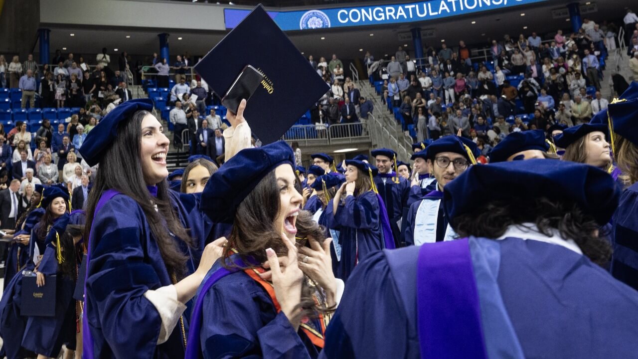 Graduate in cap and gown cheers in excitement.