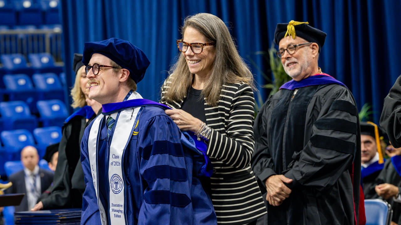 A law graduate receives his doctoral hood from his loved one