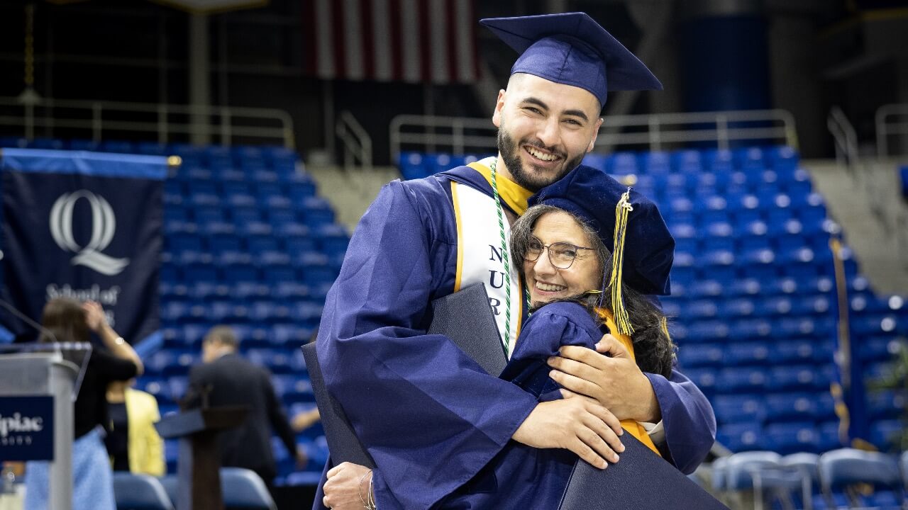 Mother and son hug and smile after both receiving their diplomas at Commencement