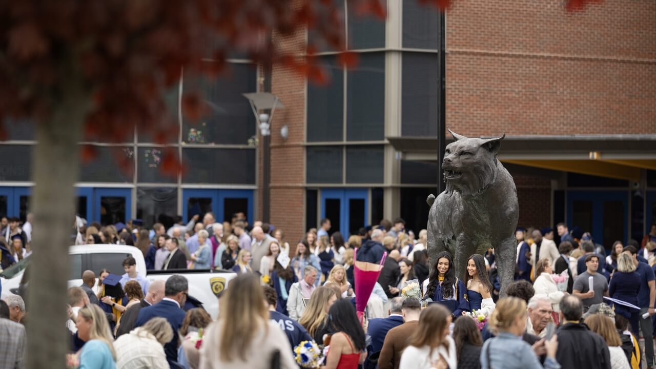 Families, loved ones and graduates smile and take photos outside of the M&T Bank Arena