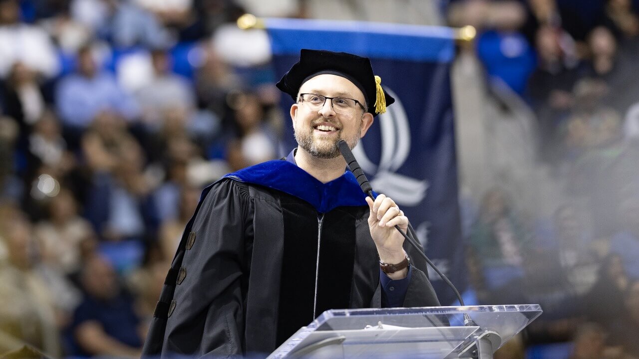 Keynote speaker stands at the podium and addresses the graduates