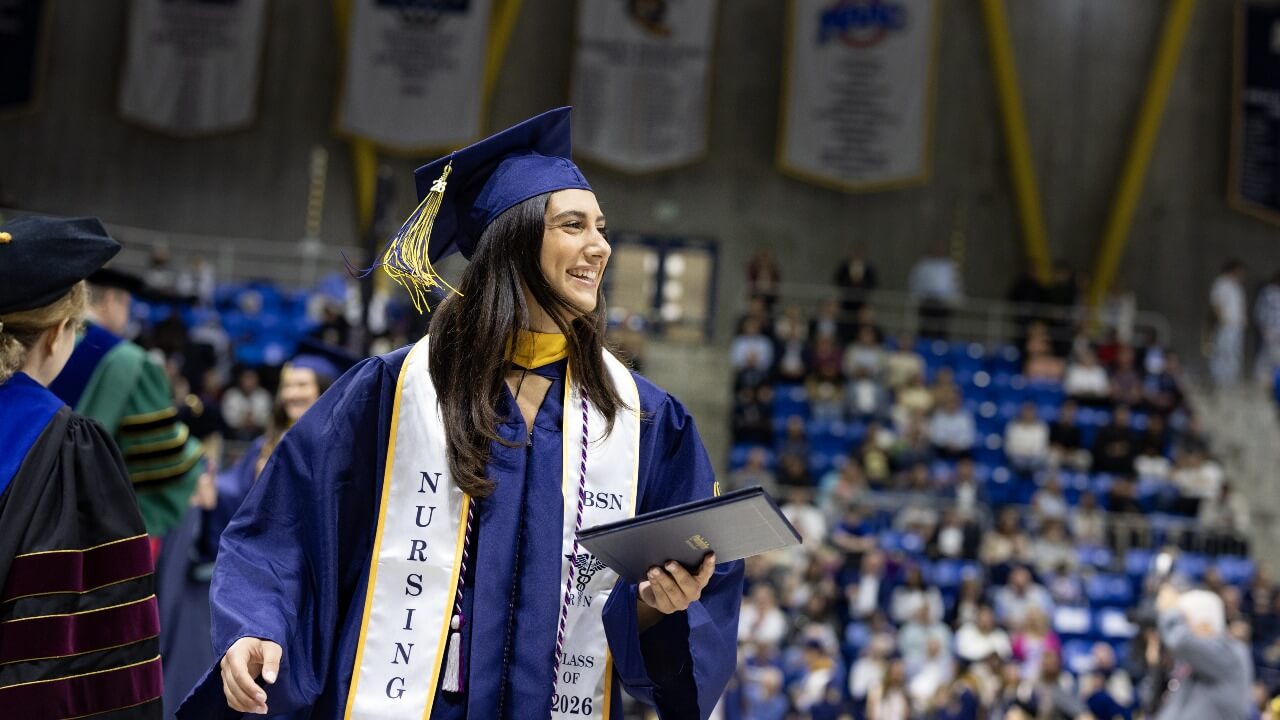 Graduate smiling while holding their diploma