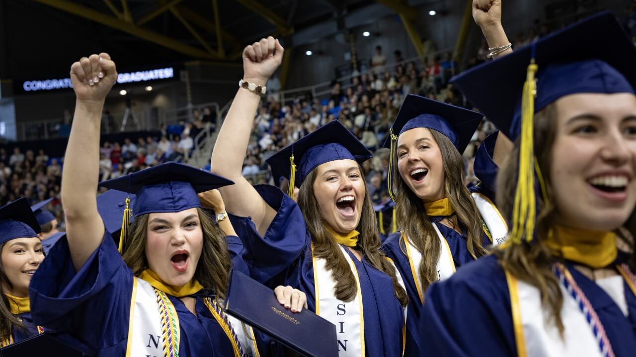 Graduates cheering and raising their hands up in the air