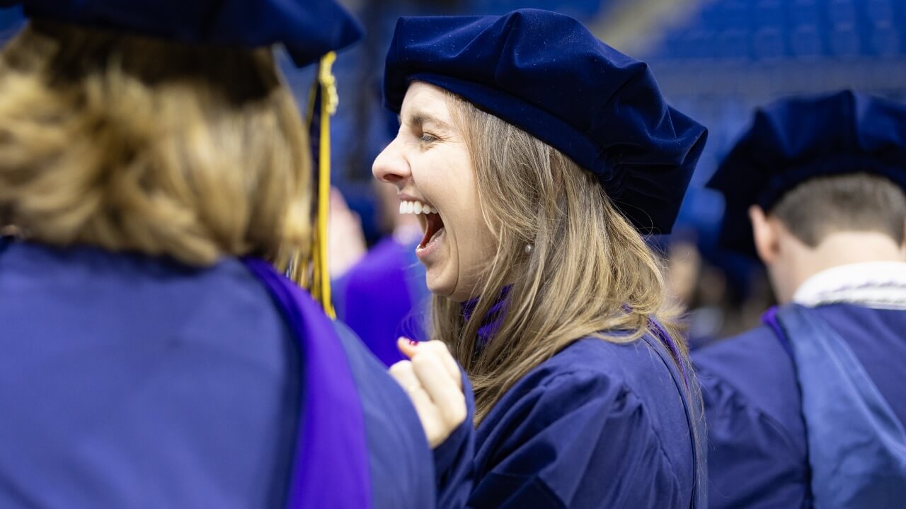 Graduate cheers next to peers during commencement