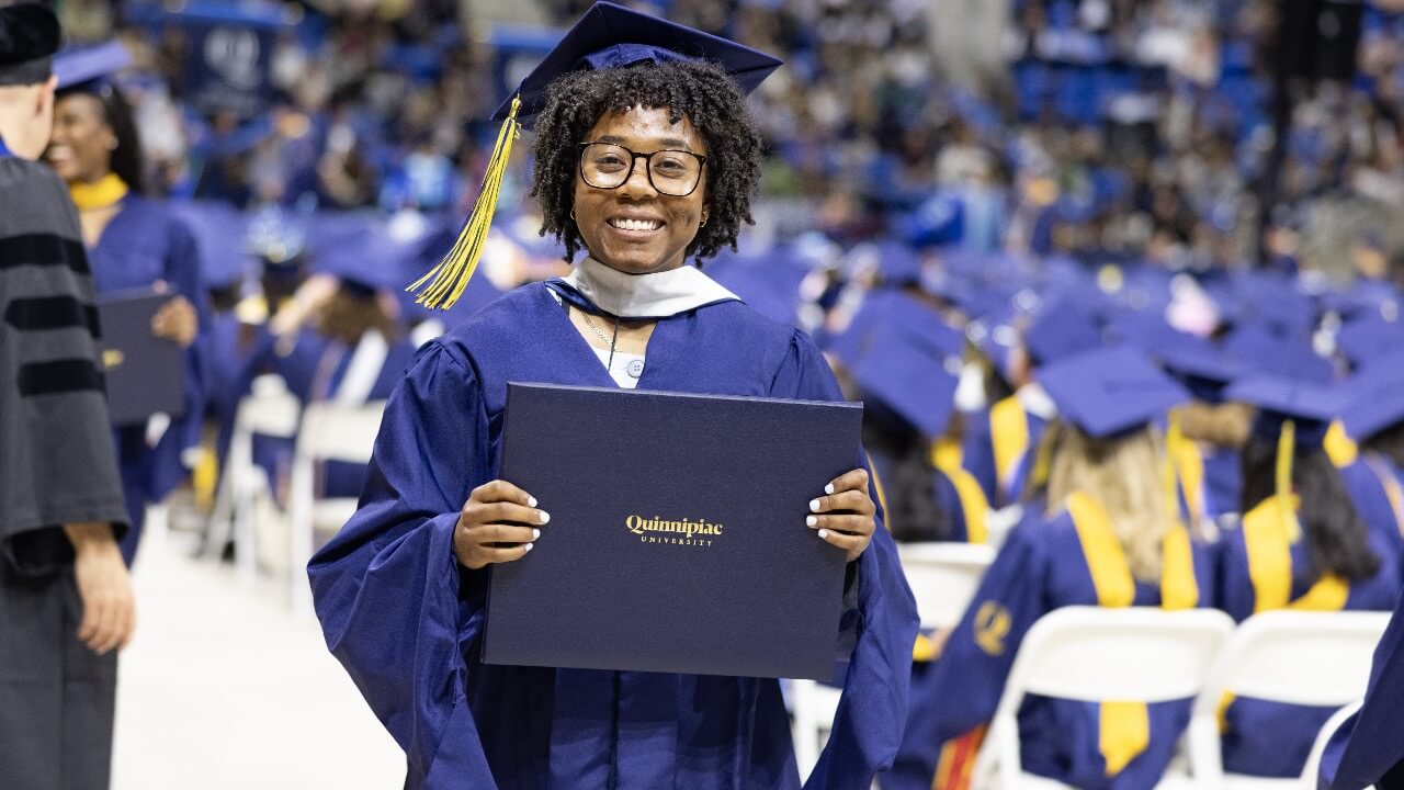 Graduate smiles and holds up diploma