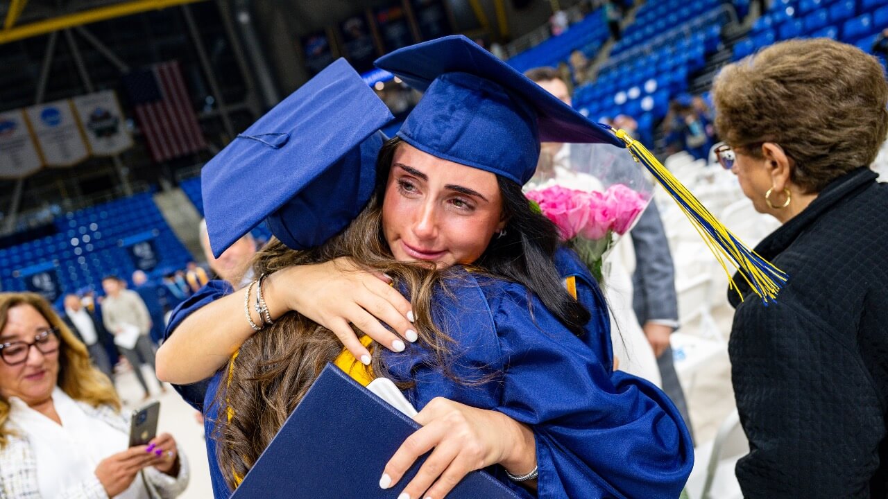 Two graduates hug at the end of the Commencement ceremony