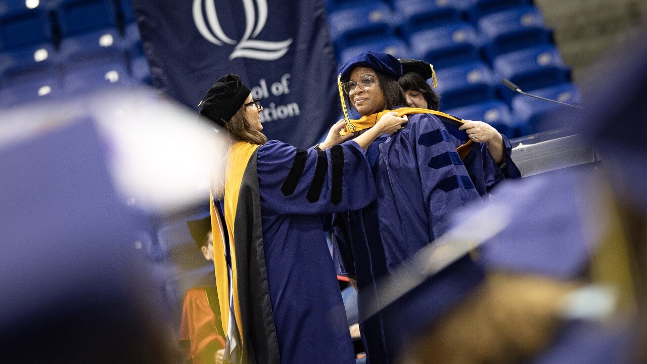 Graduate receives their hoods on stage.