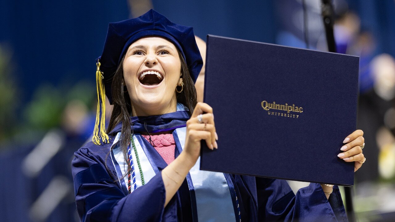 Graduate cheers while holding their diploma