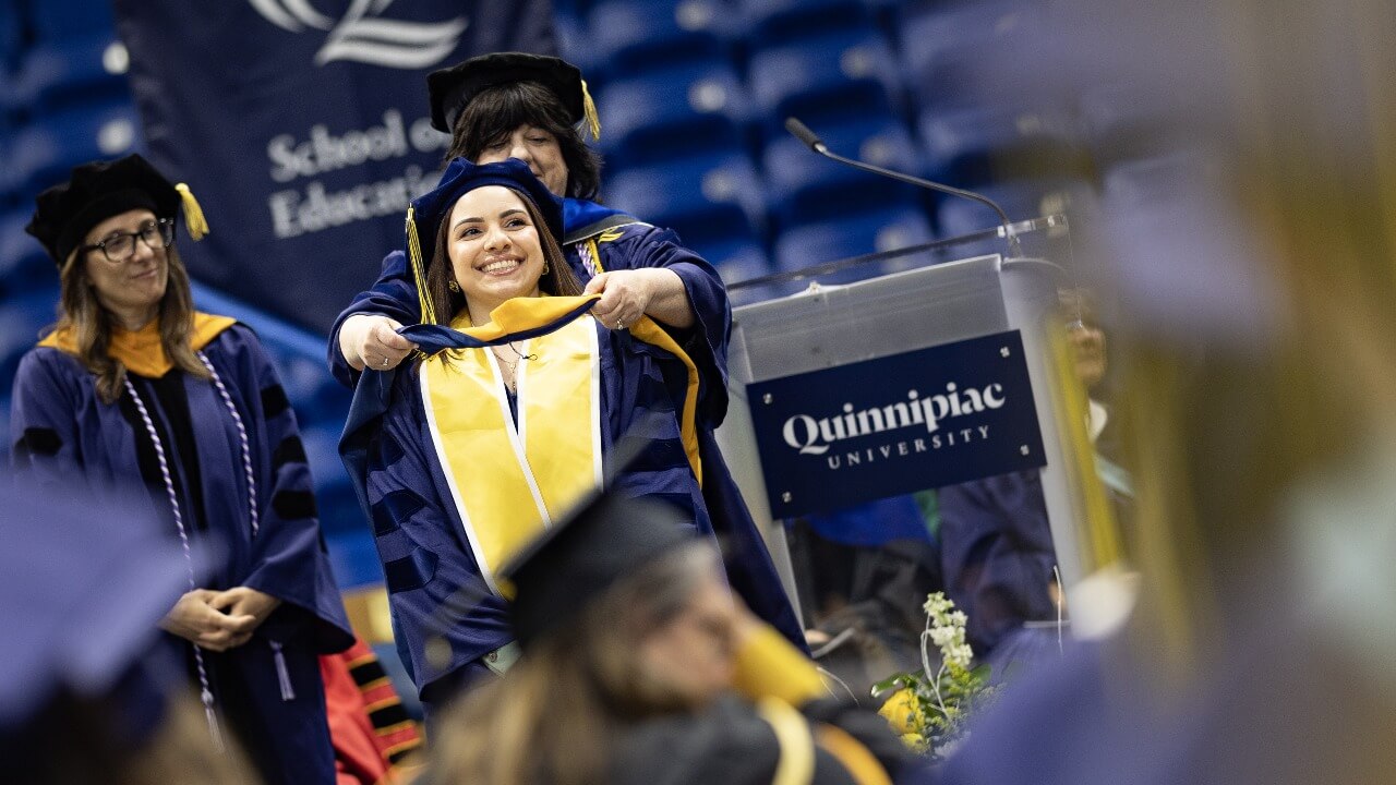 Graduate receives their hood on stage.