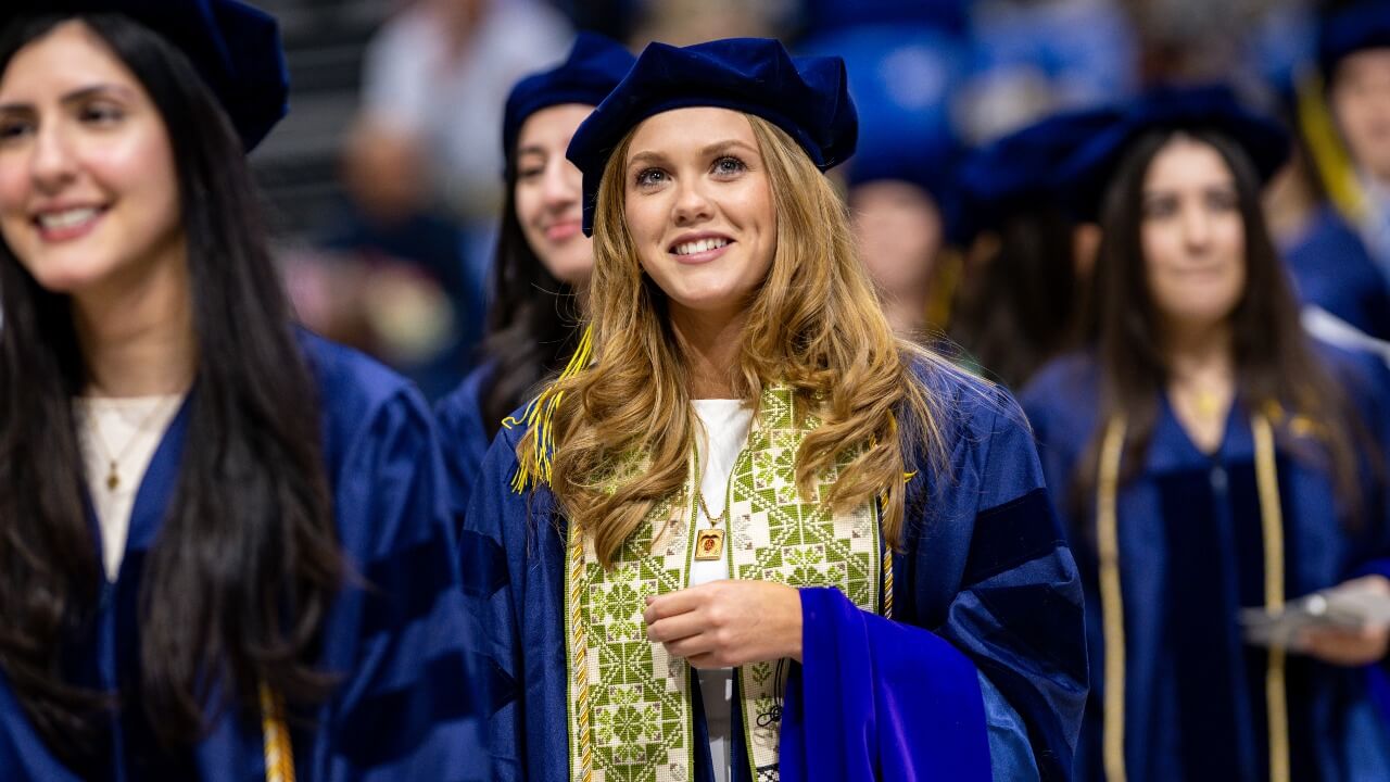 Graduate smiles during ceremony next to peers