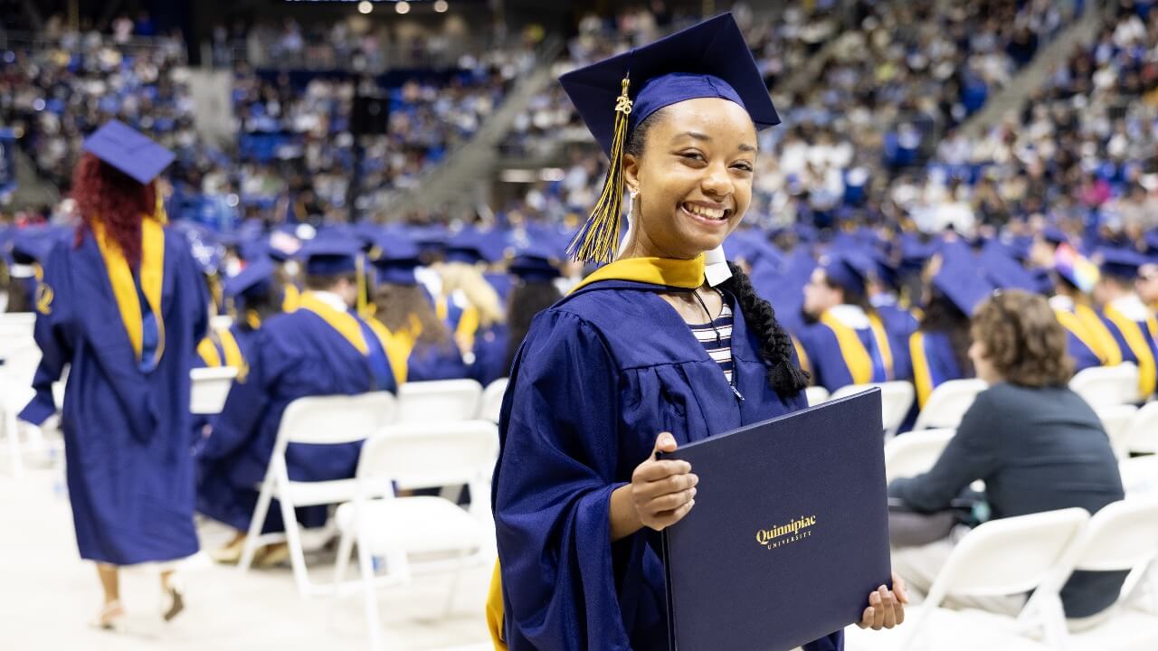 Graduate smiles and holds up diploma
