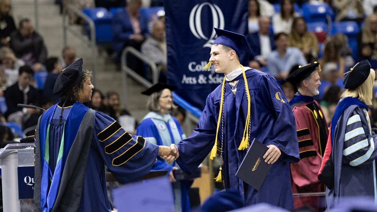 Graduate on stage shakes hand with Dean Nadine Barnett Cosby