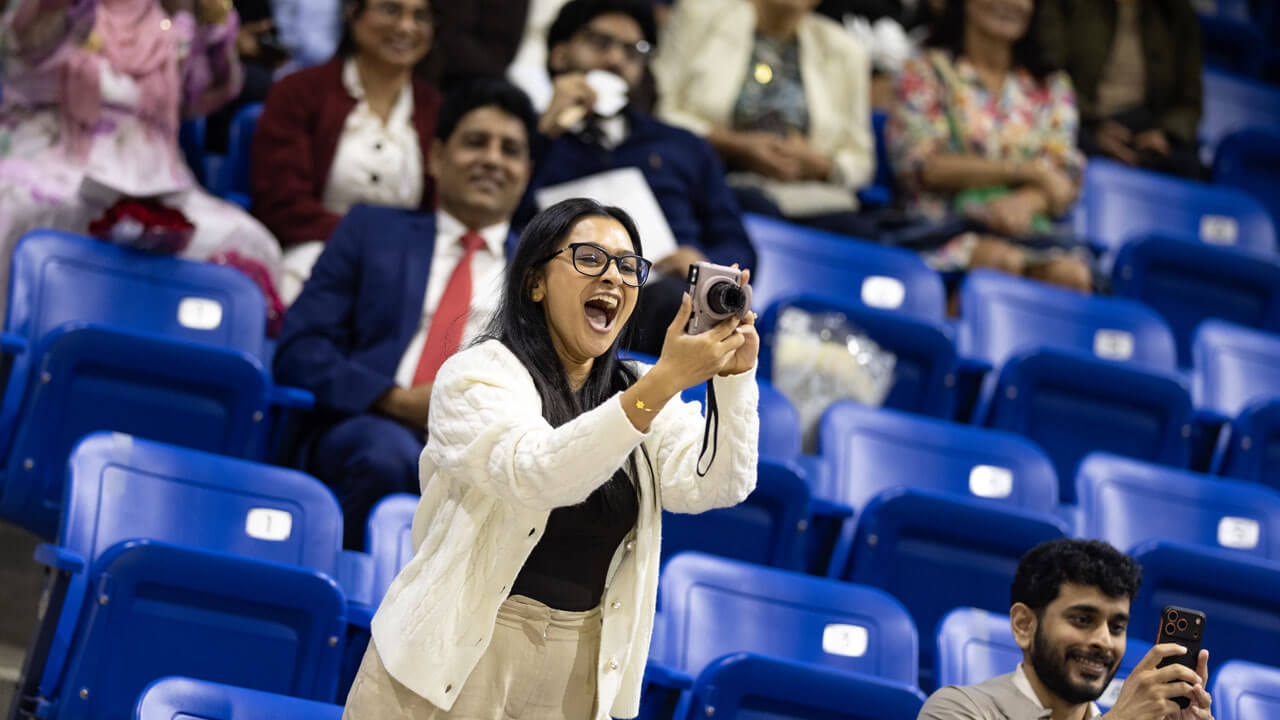 Loved one taking a photo of the 2026 School of Medicine graduates at Commencement
