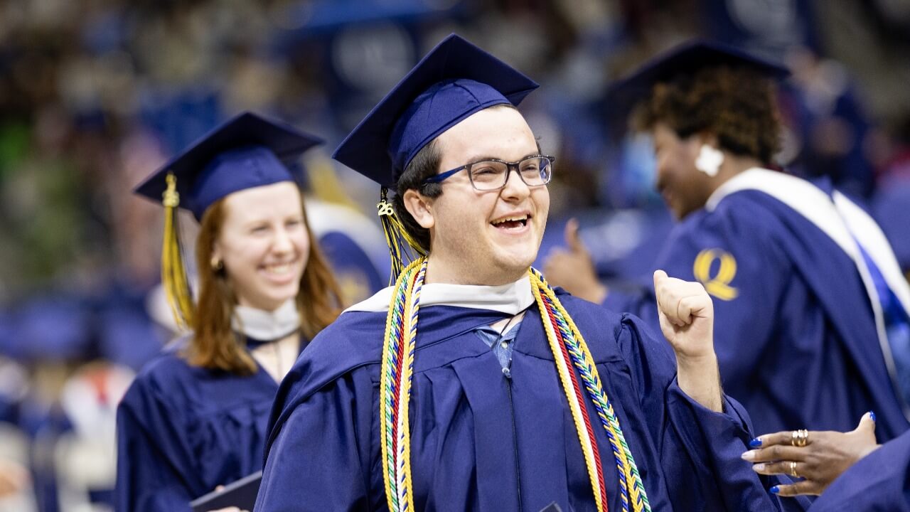 Graduate holds up fist in excitement following commencement ceremony