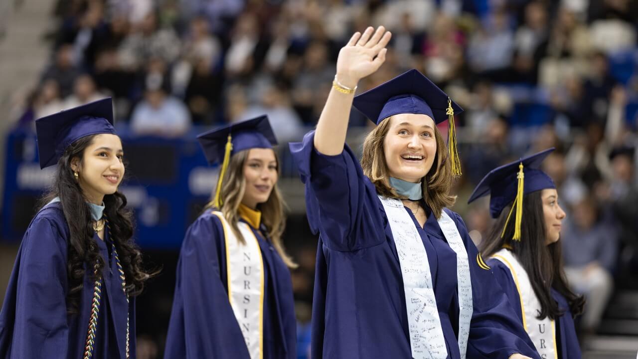 Crowd of graduates with one graduate peeking their head above the others