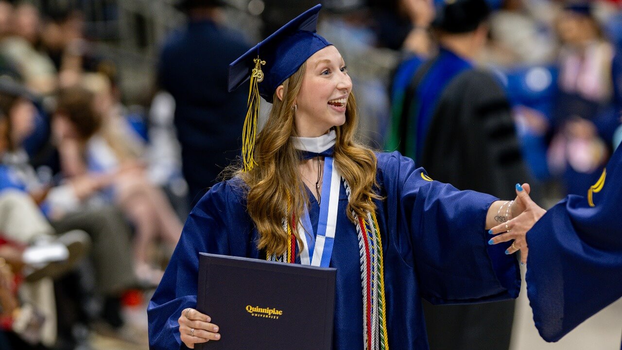 Graduate looking to their left and shaking person's hand