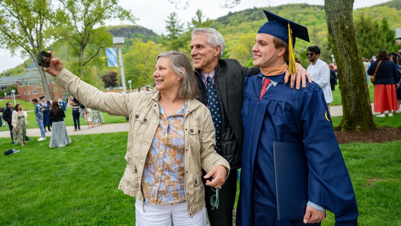 Graduate in cap and gown poses for photo with their loved ones.