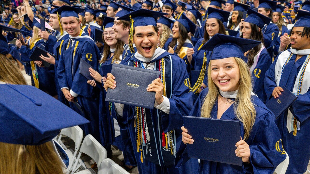 Graduate holding up diploma and cheering in the crowd