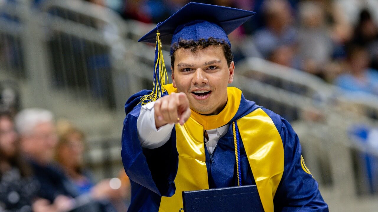 Graduate pointing at camera and smiling