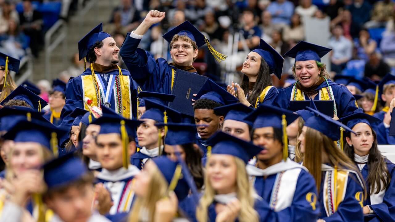 Graduates raising their arms in the air in the crowd