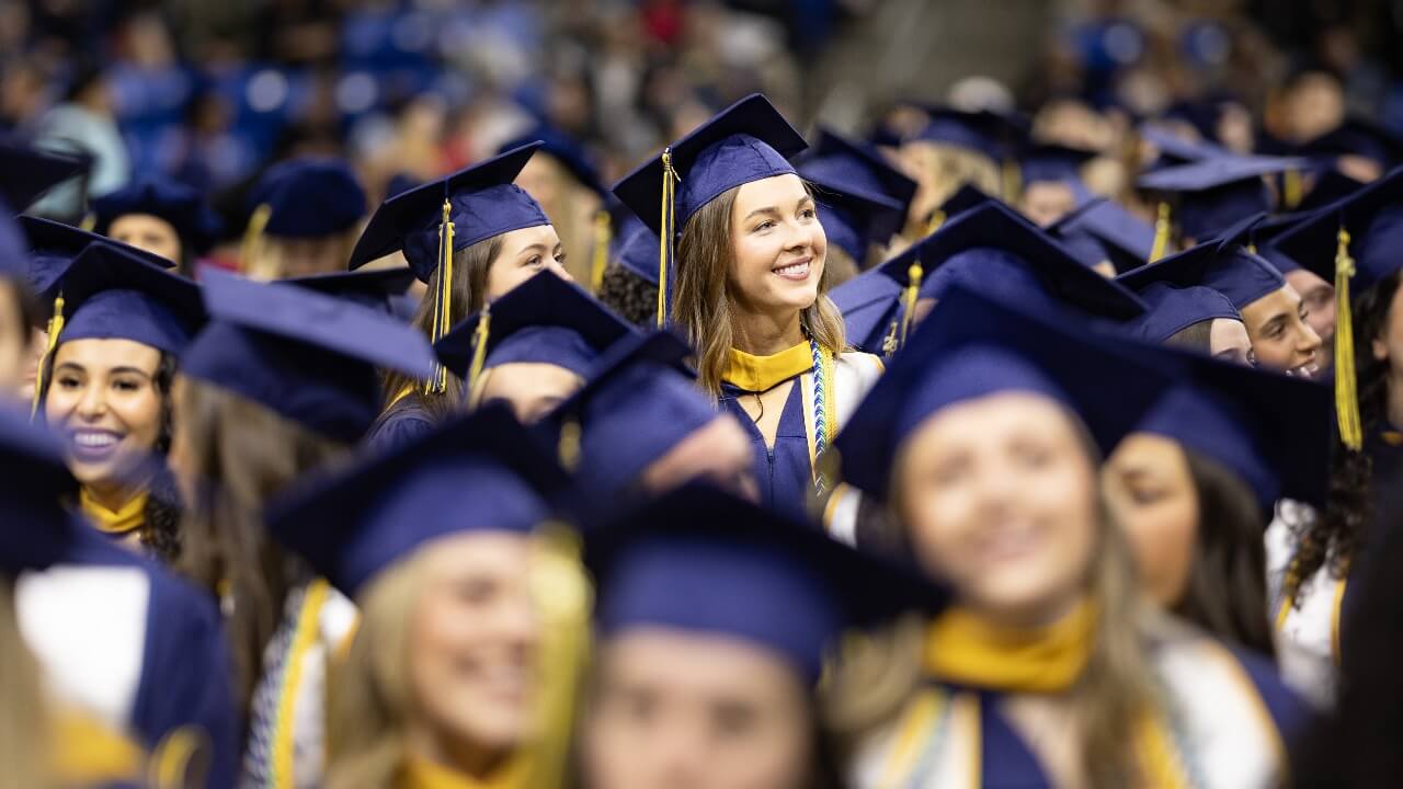 Graduates walking to the stage and waving to the guests