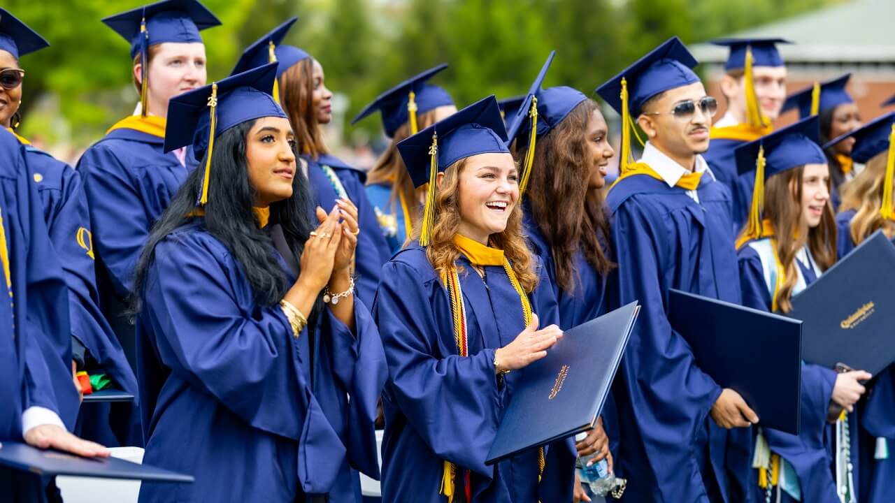 Graduates standing and clapping for their peers