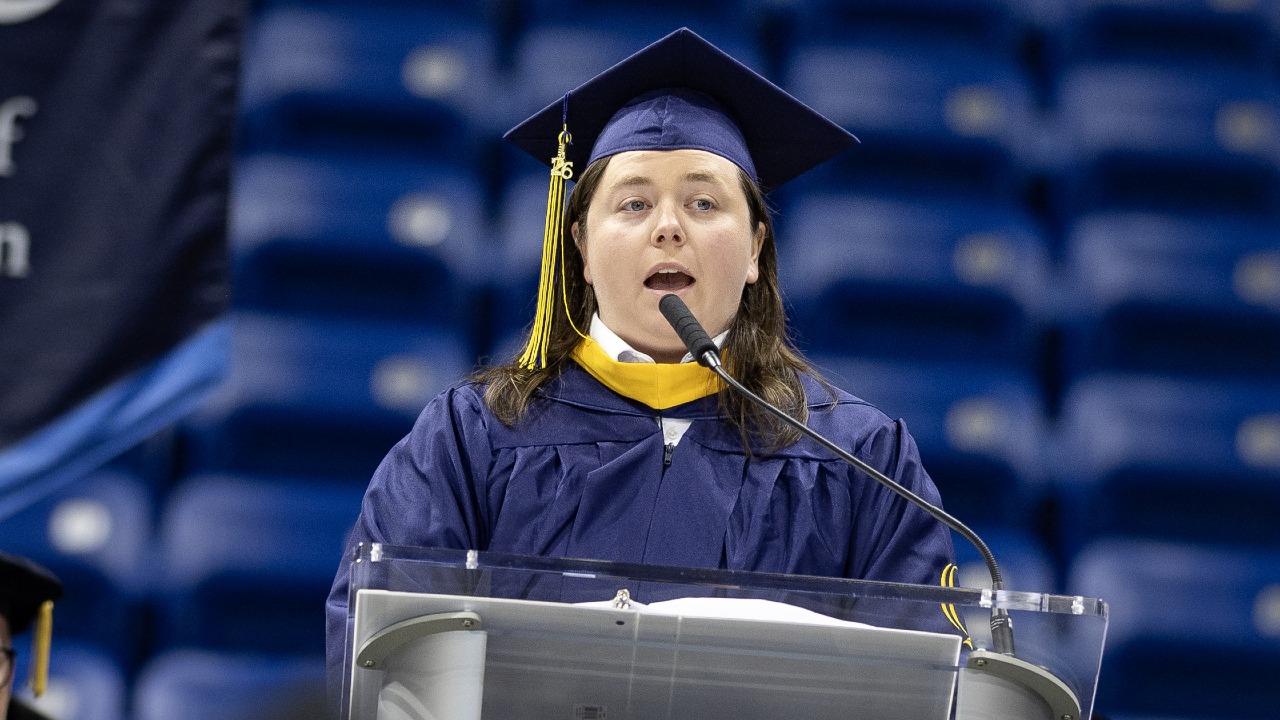 Tess Timpson address graduates while dressed in a cap and gown