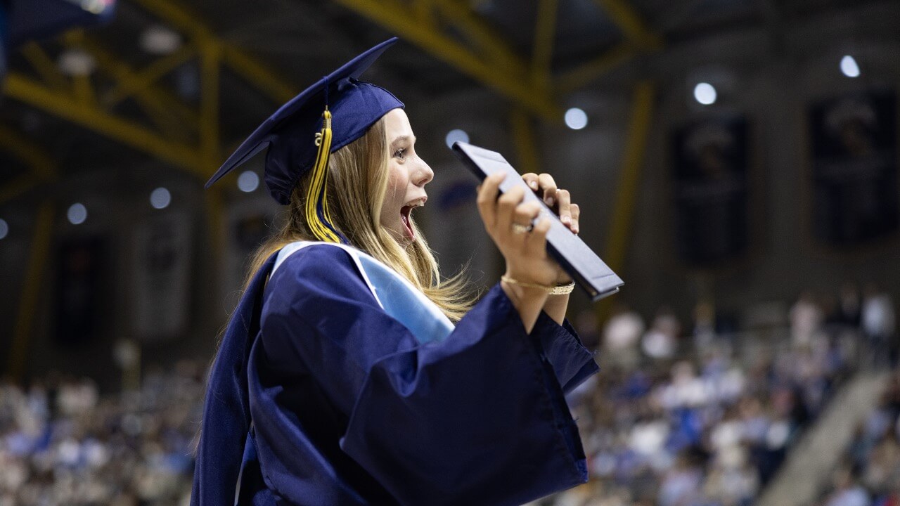 Excited graduate holds up diploma