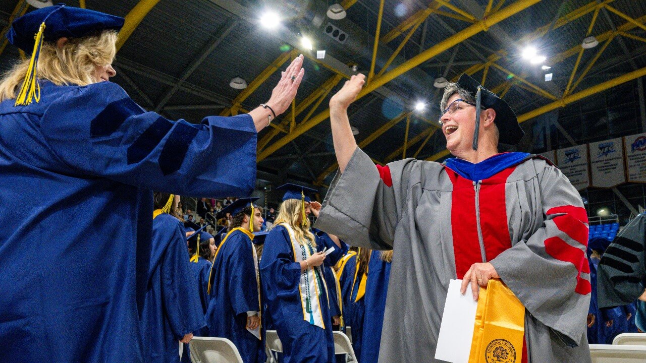 High five between a graduate and a platform party member