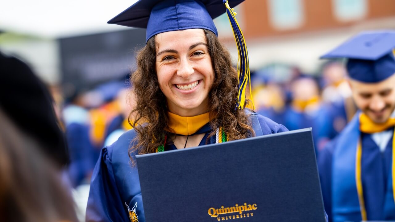 Jackie Grisdale smiling while holding up her diploma